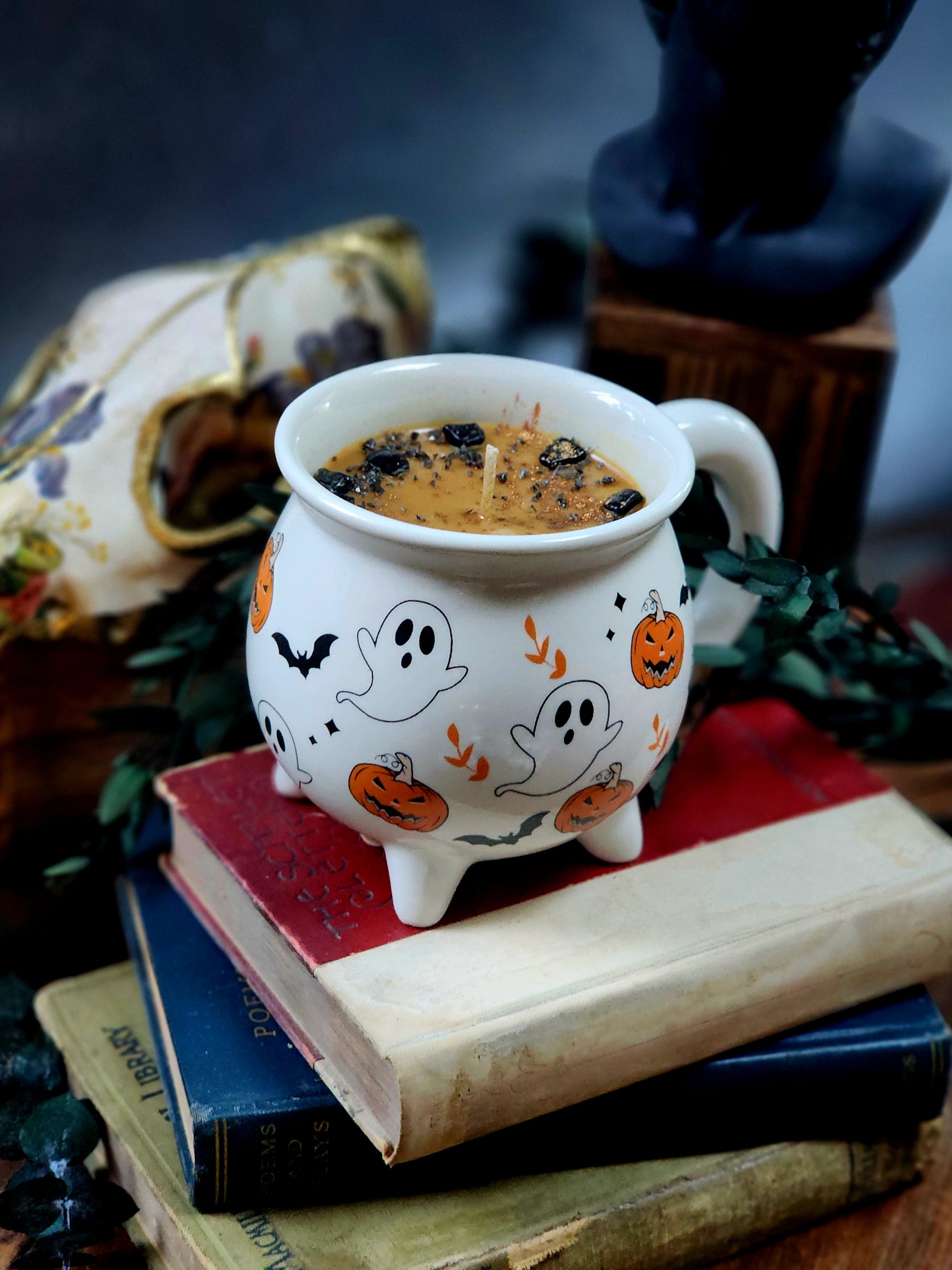 Close-up of Samhain Spice cauldron candle toppings – crystal chips and herbs on creamy light brown soy wax